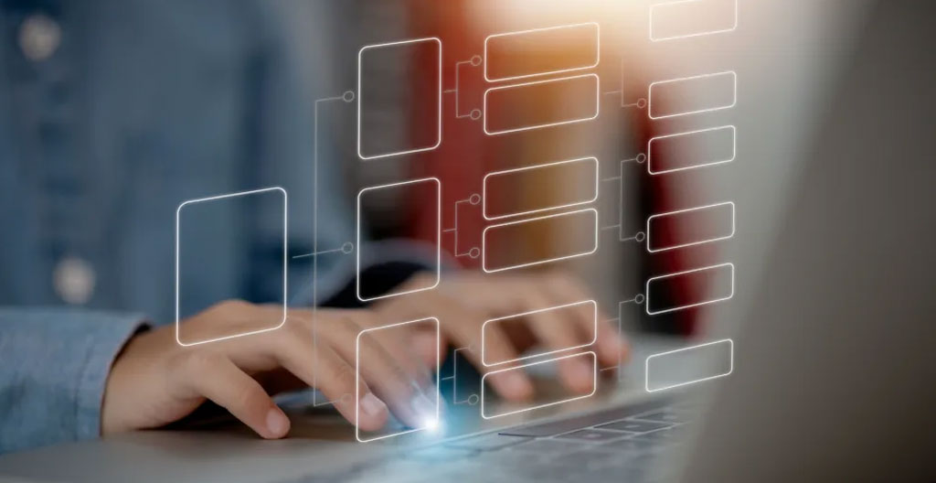 Close-up of hands typing on a laptop keyboard at a casual desk with papers and a smartphone visible