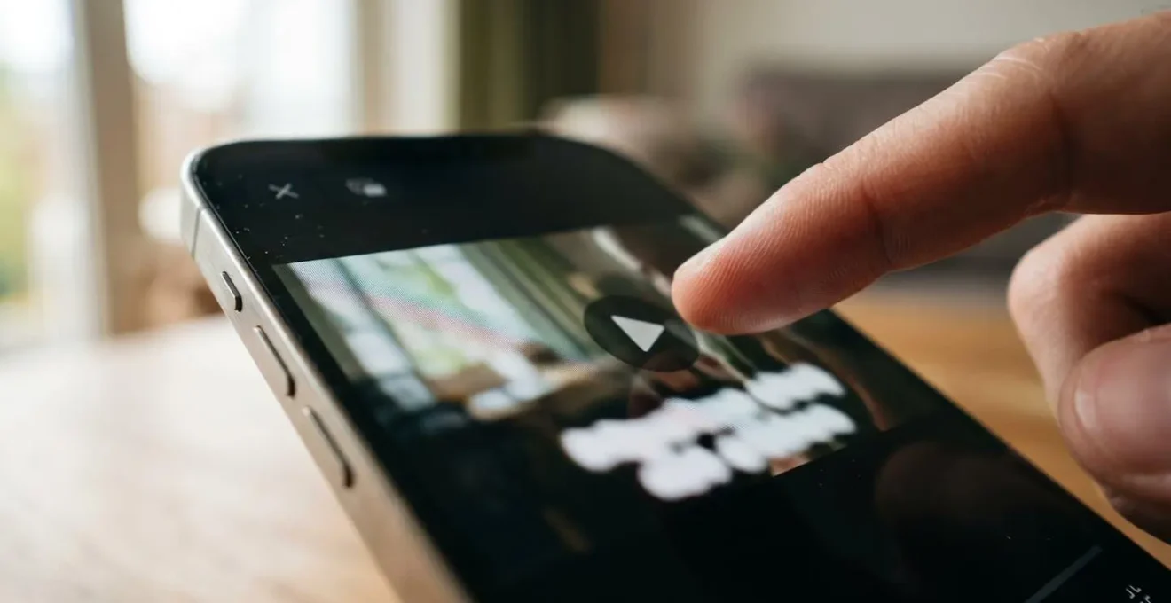Extreme close-up macro photograph of a modern smartphone screen displaying a video player with subtitle text overlay visible, with a finger hovering near the play button