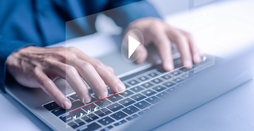 Two colleagues look at a tablet together while standing in an office corridor with natural lighting